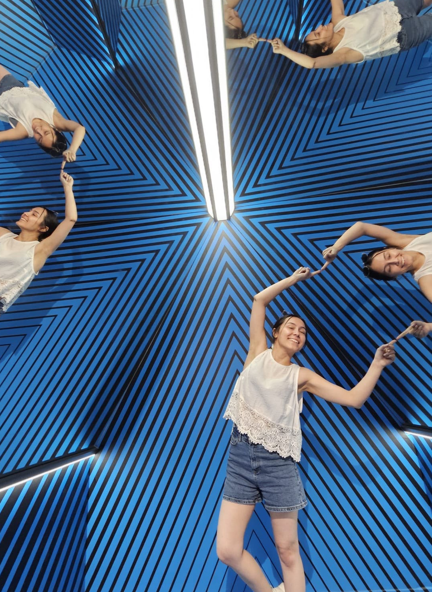 Arzu posing in a mirrored room with blue chevron-patterned walls, reflected infinitely