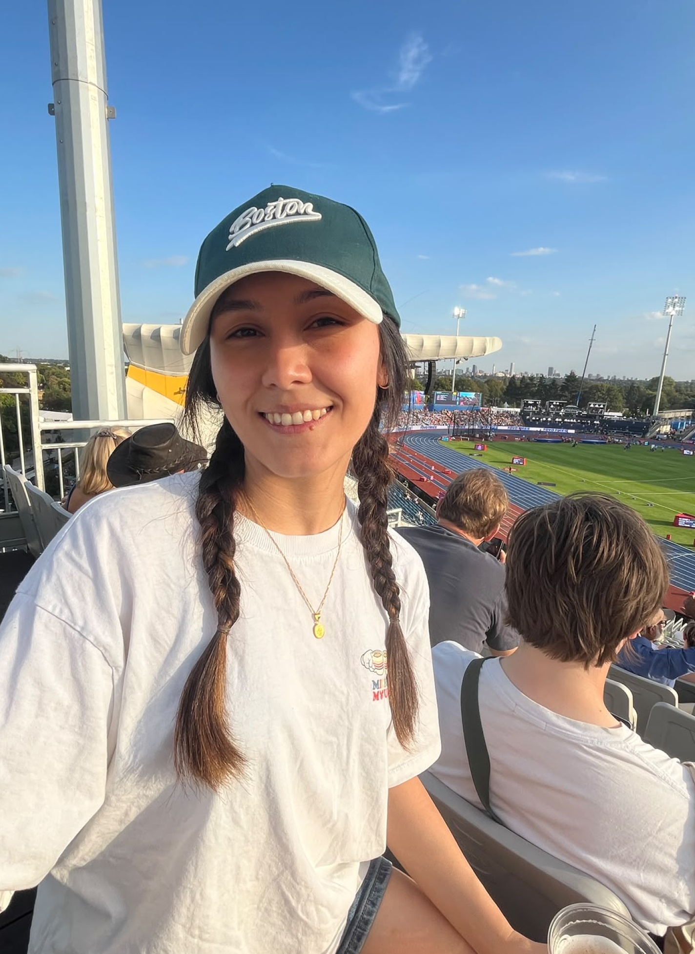 Arzu wearing a Boston cap at an outdoor athletics stadium